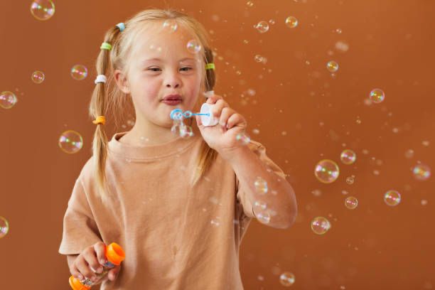 Young girl with downsyndrome blowing bubbles with a smile on her face.
